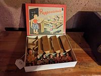 Photo showing the open box containing the teacher doll, six smaller student dolls, and six wooden desks.