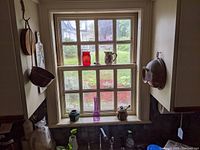 Window nook with various decorative items placed on the window sill including red glass vase, purple vase, ceramic pitcher, and other small ceramic pieces, crown molding visible above the window.