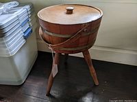 Front side view of the wooden firkin showing the legs, body, and lid with knob.