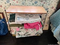 Full view of shelving unit with stored textiles demonstrating overall structure, shelving colors, and condition.