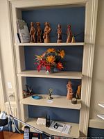 Shelf with multiple decorative figurines, flower arrangement, and small items