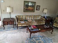 View of living room featuring pair of dark stained two-drawer end tables with cabriole legs flanking a floral upholstered sofa and matching coffee table.