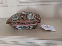 Front view of covered warming dish showing scalloped rim and floral medallion panels