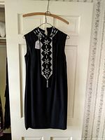 Full front view of the black sleeveless dress hanging, showing sequin panel detail.