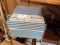 Blue and white striped vintage hat box closed, labeled M.H. Baker