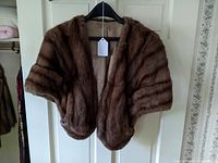 Front view of vintage brown fox fur stole hanging on hanger, showing fur texture and shape.