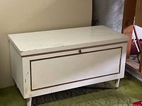 Front view of the rectangular white-painted cedar chest showing the flat lid, recessed front panel, and tapered legs.