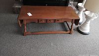 Solid wood maple coffee table viewed from front showing drawer and drop-down ends closed.