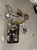Overview photo of the lot showing multiple power tools and hand tools in a metal tray and on the floor