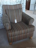 Front angled view of the upholstered armchair showing striped fabric and loose cushion on seat.