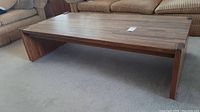 View of full coffee table from side showing plank-style top and U-shaped end leg