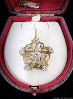 Pendant displayed in red velvet jewelry case showing filigree design and diamond placement.