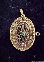 Front view of oval locket with filigree detail and central turquoise