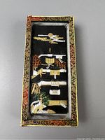 Top-down view of the ink stick displayed in its decorative fabric-lined box with colorful brocade border.