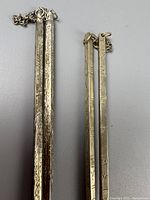 Two pairs of Qing Dynasty vintage silver chopsticks laid side by side, showing chain connections and detailed engravings.