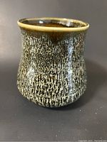 Side view of vase showing textured flammable glaze on exterior surface in mixed brown, black, and beige colors.