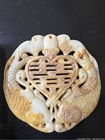 Front view showing the intricate carving of two dragon or fish creatures surrounding a heart-shaped motif with characters.
