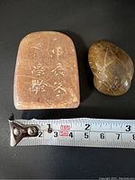 Both stones laid flat with measuring tape showing length about 6cm for the larger seal