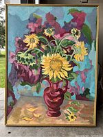 Full view of the oil painting showing sunflowers in a red vase with a multi-colored background and thin gold frame.