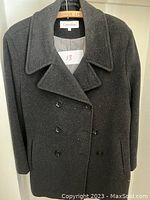 Black double breasted peacoat with button front and collar on hanger