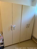 Photo of two closed white storage cabinets side by side with silver handles, showing the exterior design.