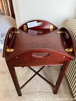 Photo of the assembled brown/red wood table with top in square form, showing brass hinges and handles.