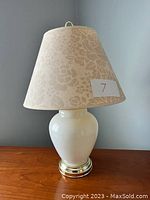 Full view of white ceramic ginger jar lamp with off-white floral print lampshade.