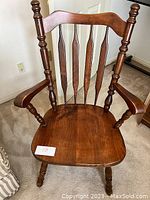 Front view of wooden chair showing spindle back, armrests, and seat