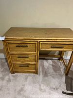 Full view of the solid wooden desk showing four drawers on the left side with bamboo-style trim and metal handles.