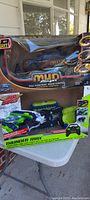 Two RC vehicles in their original boxes: the black Mud Stinger off-road truck and the green/blue Thunder Trax transforming vehicle with its controller visible.