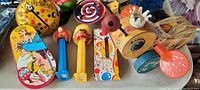 Photo showing a variety of vintage toys including colorful noisemakers, PEZ dispensers shaped as characters, and a clown-themed noisemaker toy.