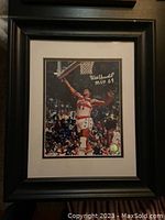 Framed and matted signed Wes Unseld basketball photo under glass in black frame.