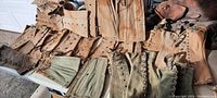 Collection of antique leather and fabric military leg covers laid out on a surface, showing a variety of designs and fastening methods.