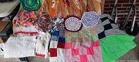 Photo showing colorful crochet dollies, white crochet pieces, and a pastel patchwork quilt top laid out showing patterns and textile details.