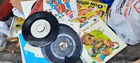 Image showing vintage 45 RPM vinyl records and children's music record covers in colorful sleeves piled together.
