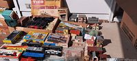 Photo showing assorted HO scale model trains, boxes, and buildings arranged on a table.