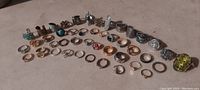 Photo showing all 45 estate rings arranged in rows on a flat surface; diverse styles, sizes, and metals visible, many rings with stones or decorative features
