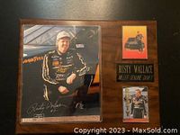 Wood plaque with signed photo of Rusty Wallace, two cards, and nameplate, angled on black surface.