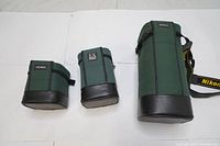 Photo of three soft padded green camera lens cases of varying sizes, arranged left to right from smallest to largest, with Sigma and EX branding visible.
