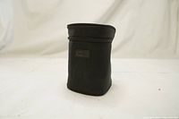 Side view of the black padded Sigma lens case showing the cylindrical shape and smooth fabric.