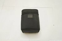 Black padded soft lens case standing upright, showing overall shape and dimensions.