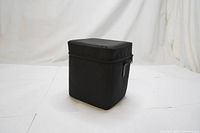 Full view of the black rectangular camera lens case with zippered top and structured foam-sided body.