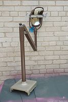 Full view of the vintage dental exam light showing the base, adjustable arm, and light head mounted on a stand.