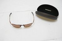 Photo of sunglasses and hard case on flat surface showing frame and lens shape