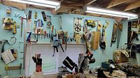 Wide view of pegboard wall with hand saws, clamps, screwdrivers, and hardware storage