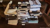 Stack of about 27 decorative collector plates in cardboard storage boxes on brown couch