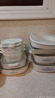 Stacked set of Corningware dishes with Blue Cornflower pattern showing multiple sizes and shapes with lids, white ceramic and glass lids visible