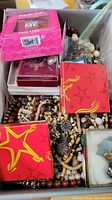 Box filled with assorted jewelry including wooden bead necklaces and boxed items