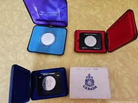 Three commemorative Canadian silver dollar coins in individual display cases.