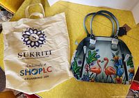 Photo showing the Sukriti branded reusable shopping bag and the hand-painted leather purse featuring flamingo artwork.